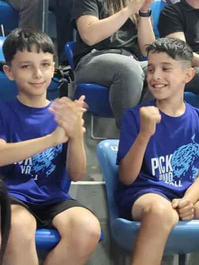 Két fiú tapsol és örömmel szurkol a PICK Aréna lelátóján a PICK Szeged bajnoki döntőjén.
