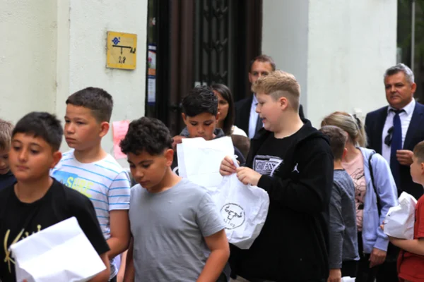 A zenekar gyerektagjai fehér ételes csomagokkal indulnak a Szent István parkban tartott ebédhez.