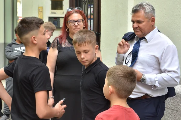 A Sugó Tamburazenekar vezetője és gyerektagjai beszélgetnek egy budapesti épület előtt a fellépés napján.