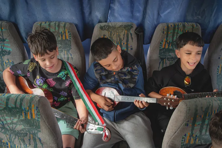 Három fiú ül a busz ülésein hangszereikkel, és útközben zenélnek, miközben Budapestre tartanak az Országházba.