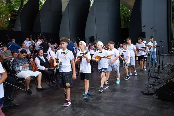 A Sükösdi SUGO Tamburazenekar fiataljai sorban vonulnak át a színpadon hangszereikkel a koncert előtti főpróbán.